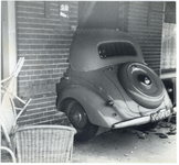 603925 Afbeelding van een auto die een woning (café?) is binnengereden.N.B. De afbeelding maakt deel uit van een serie ...